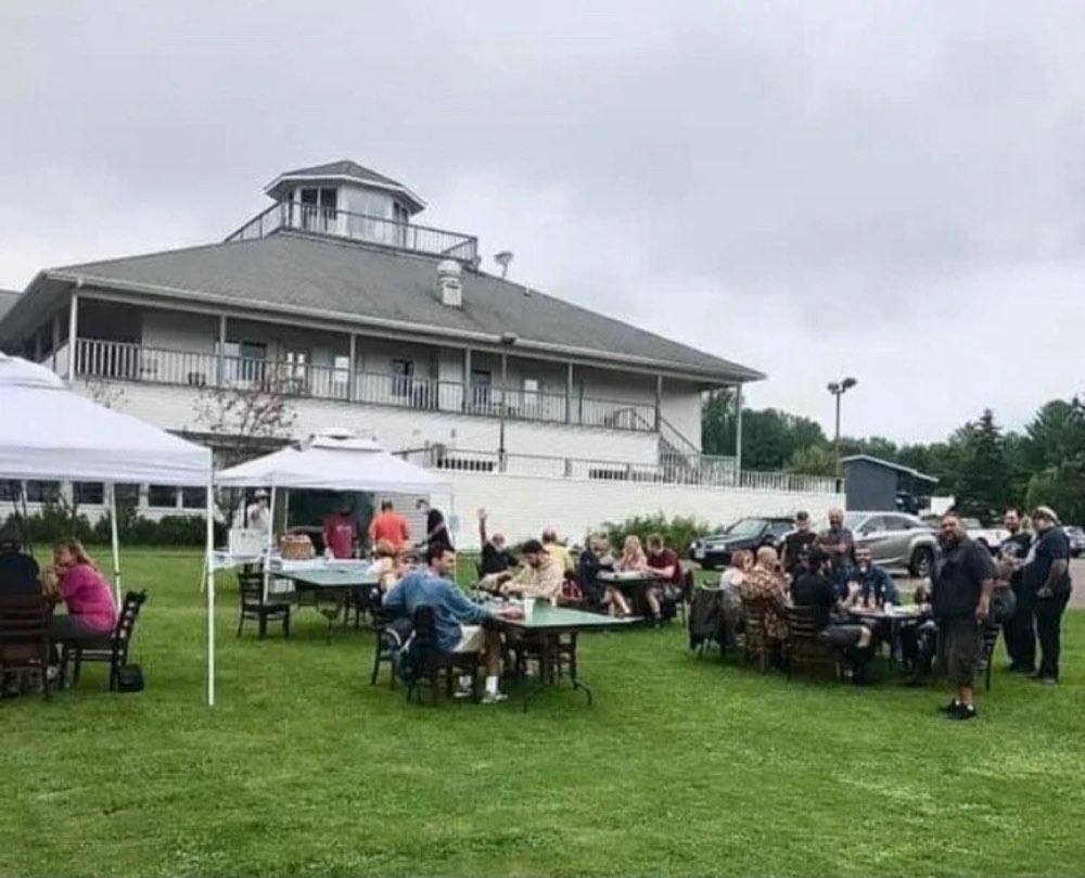 Guests at tables under white tents in the yard