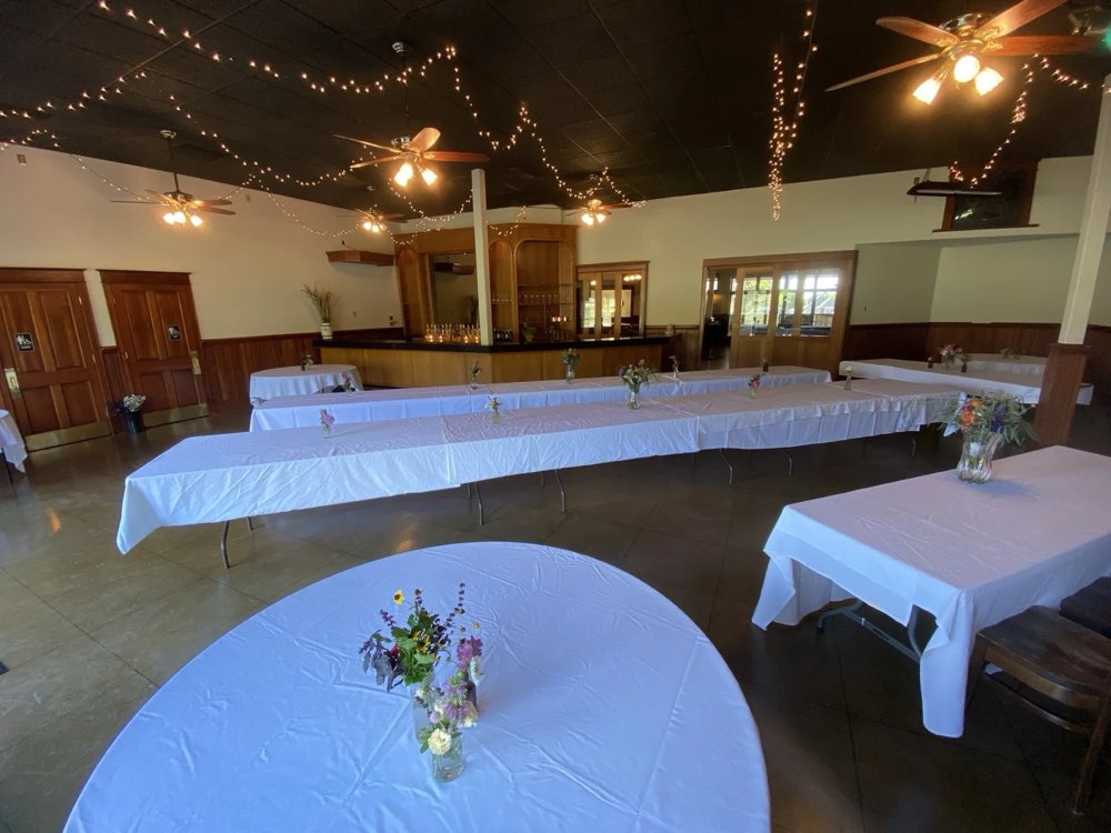 The back bar room with round tables, string lights and the stage
