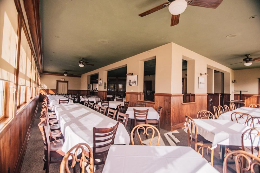 The dining room set with white linens and rows of windows